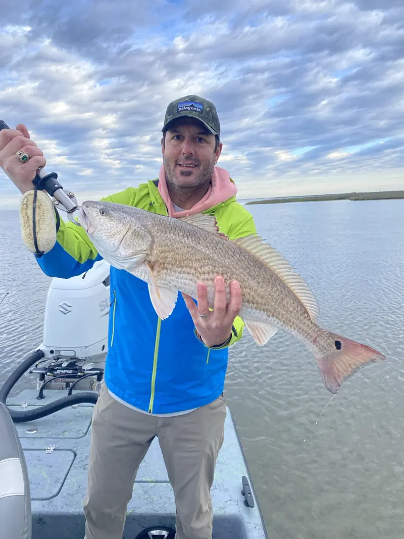 Client holding a large redfish aboard the boat